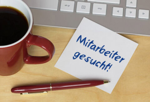 Bewerbungsschreiben für Bauunternehmen auf Schreibtisch mit Kaffee und Tast.