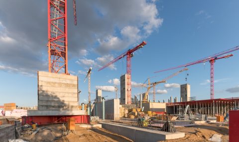 Baustelle im Bauwesen mit mehreren Kränen und Baufortschritt.