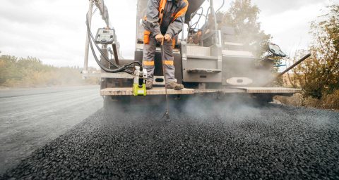 Asphalt wird auf Straße ausgelegt in Bauarbeiten.
