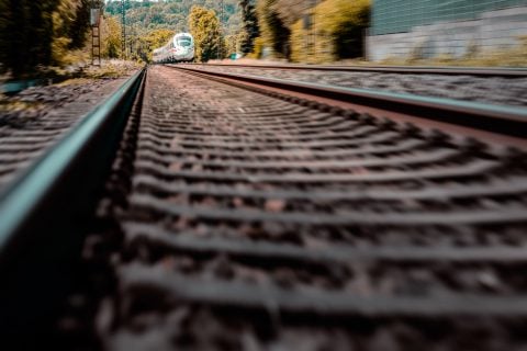 Hochgeschwindigkeitszug auf Bahngleisen in ländlicher Umgebung.