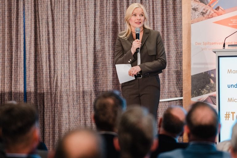 Frau spricht bei Bauveranstaltung vor mittelständischen Bauunternehmen.