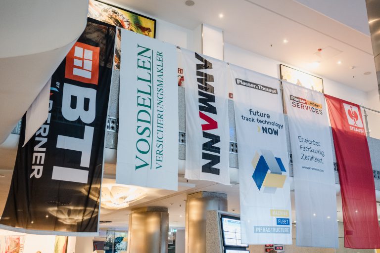 Bunte Banner mit Bau- und Infrastrukturunternehmen im Innenraum.