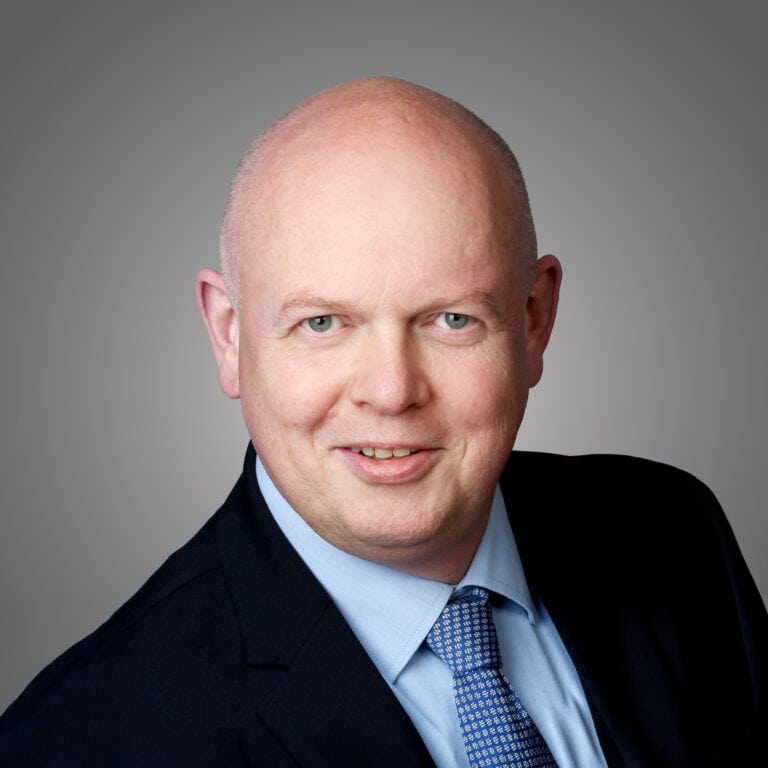 Porträt eines Mannes in Anzug vor grauem Hintergrund, Bauwirtschaft.