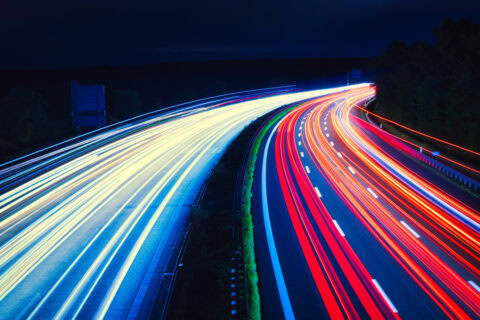 Schnelle Autobahn mit Lichtspuren bei Nacht, Bauwirtschaft-Kontext.