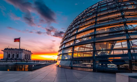 Moderne gläserne Architektur des Deutschen Bundestages bei Sonnenuntergang.