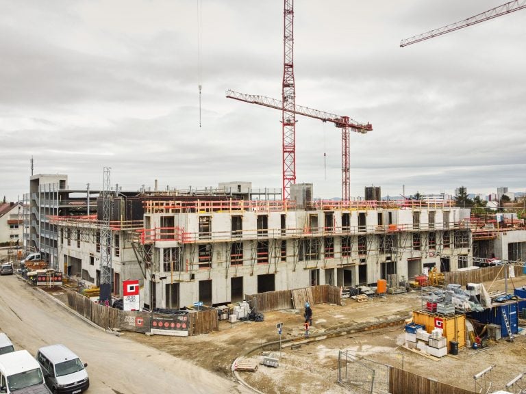 Mehrstöckiges Bauprojekt mit Kranen und Bauarbeitern.
