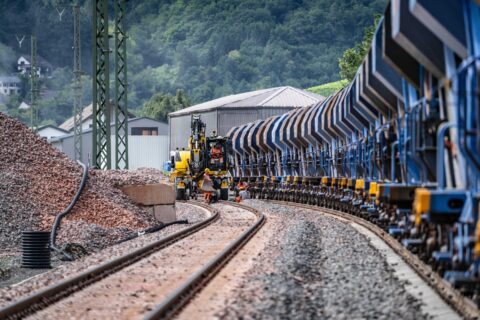 Bauarbeiten an einer Bahnstrecke mit Güterwagen und Baumaschinen in der Bau.