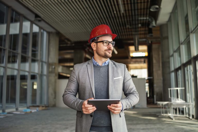 Baustellenleiter mit Tablet auf der Baustelle, Bauwirtschaft-Kontext.