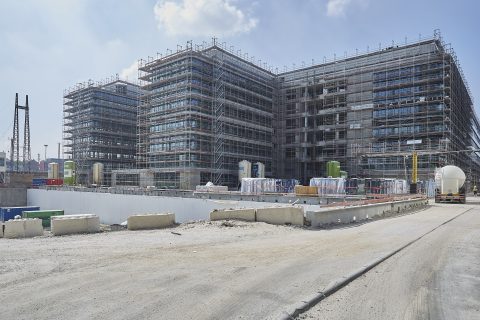 Baufortschritt eines großen Gebäudes auf einer Baustelle, Gerüste und Bauge.