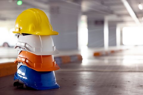 Stapel von Bauhelmen in verschiedenen Farben in einer Baustellenumgebung.