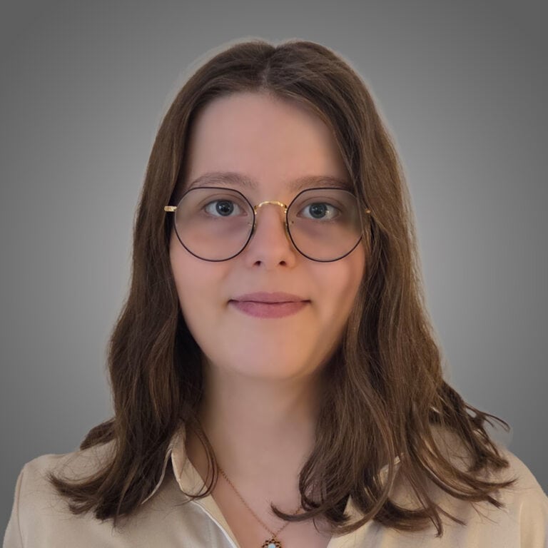 Porträt einer Frau mit Brille vor grauem Hintergrund in der Baubranche.