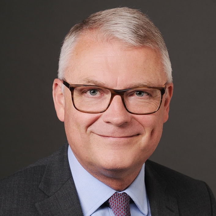Mann in Businessanzug und Brille, professionelles Porträt.