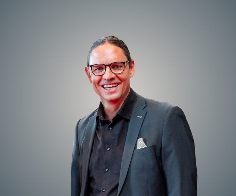 Porträt von Moritz Willke in Businesskleidung vor neutralem Hintergrund.