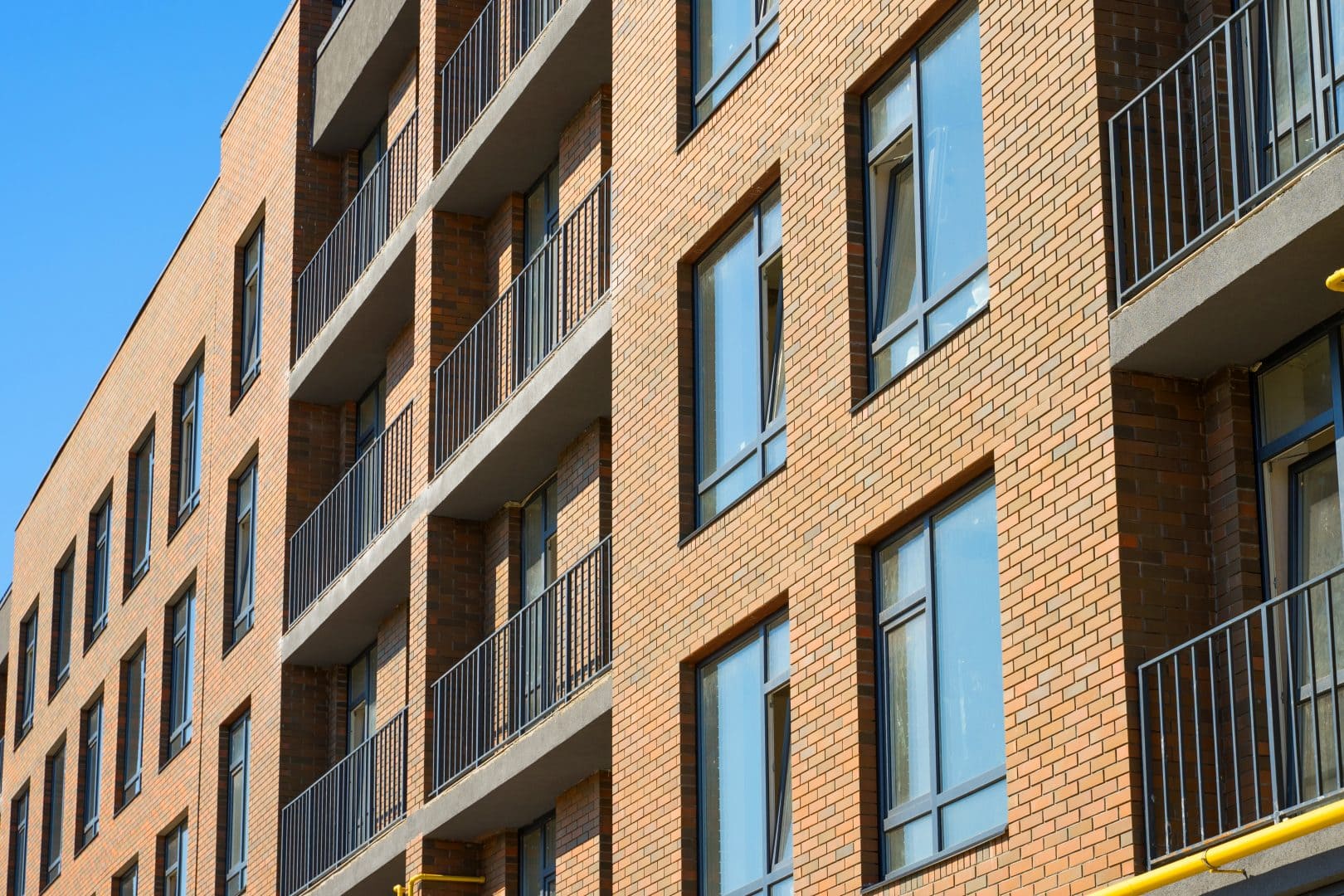 Moderne Mehrfamilienhäuser mit roten Ziegelwänden und Balkonen.