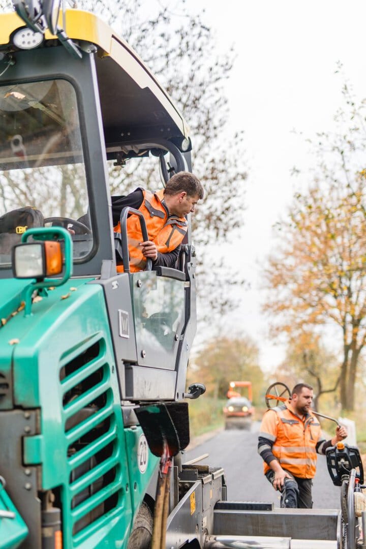 Bauarbeiter bei Arbeiten mit Baumaschine auf der Straße.