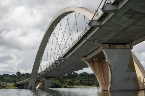 Moderne Brücke über einen Fluss mit Bäumen im Hintergrund.
